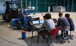 Agricultural engineering researchers testing and evaluating mechanized farming equipment in a university laboratory.